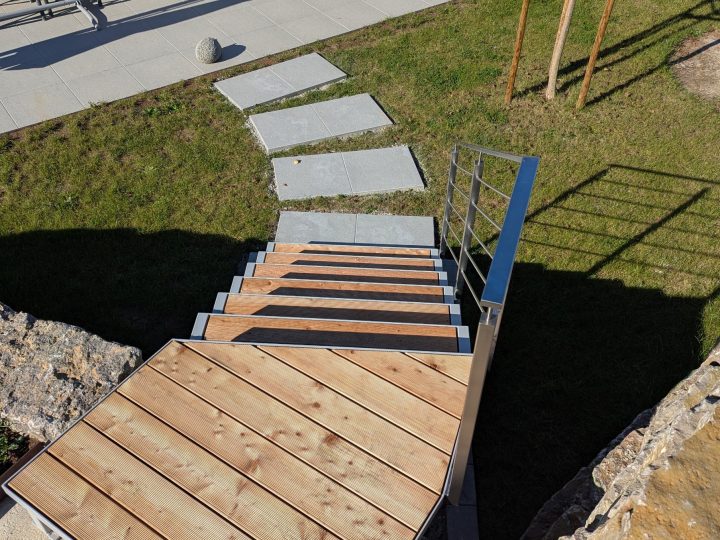 Edelstahlgeländer an pulverbeschichteter Treppe mit Holzstufen.